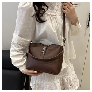 Brown bucket bag with silver lock closure and dual straps shown on a model