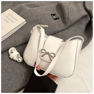 Détail d'un sac à main en cuir blanc avec un nœud métallique argenté élégant