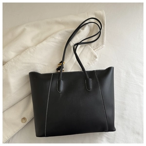 Detail of black tote bag featuring white contrast stitching and floral silk scarf accessory