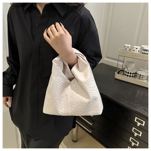 Detail of off-white woven leather tote bag with iconic knotted handle and checkerboard pattern