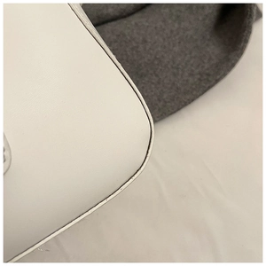 Gros plan sur la texture du cuir blanc et les coutures précises du sac sous le bras