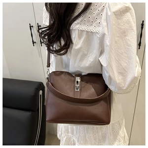 Brown leather bucket bag with silver metal buckle and dual straps on a female model