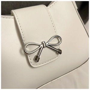 Gros plan du sac en cuir blanc avec une boucle décorative en forme de nœud en métal argenté