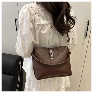 Detailed view of brown leather bucket bag showing silver twist lock and texture