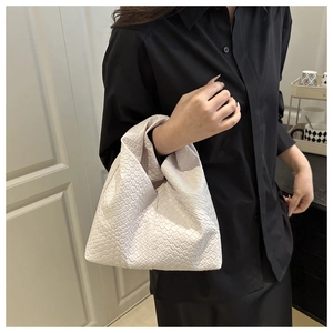 Close-up of beige woven leather knot bag showing intricate texture and handle detail