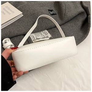Gros plan sur les coutures du fond renforcé et le cuir blanc lisse du sac sous le bras