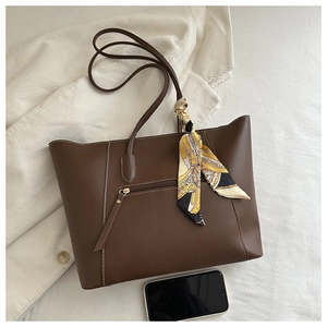 Detail of dark brown tote bag with white stitching and printed silk scarf accessory