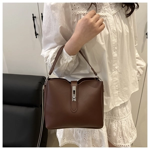 Detail view of a brown bucket bag with silver metal latch lock and top handle