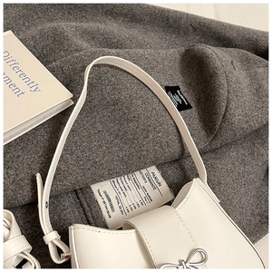 Détail du sac sous le bras en croissant blanc avec nœud en métal argenté et cuir lisse