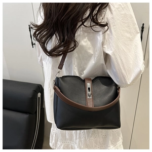 Side view of black bucket bag with brown straps worn by a model in a modern interior