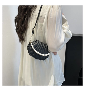 Détail du sac de soirée noir en forme de coquillage avec chaîne de perles et bandoulière