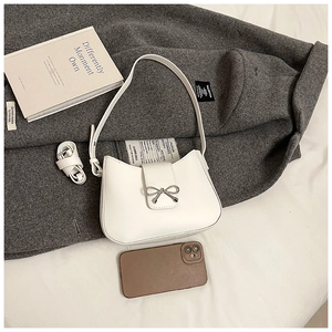 Détail du sac demi-lune blanc avec nœud en métal argenté et bandoulière réglable