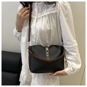 Detailed view of bicolor bucket bag with silver clasp carried by model in lace outfit