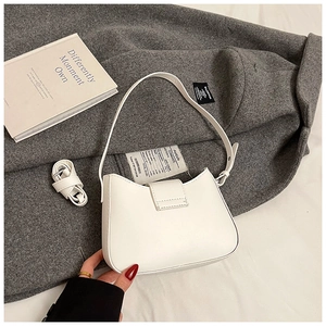 Détail d'un sac demi-lune blanc avec bandoulières réglables sur fond en laine foncée