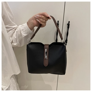 Detail of a vintage contrast bucket bag featuring a silver metal twist lock and brown handle
