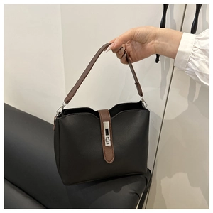 Close-up of contrast leather bucket bag featuring silver buckle and wavy edge details