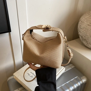Elegant khaki straw woven crossbody bag with gold buckle on a stylish travel background