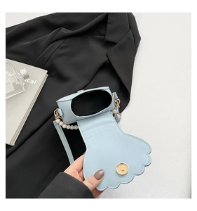 Detail of blue shell-shaped evening bag showing interior lining and pearl handle