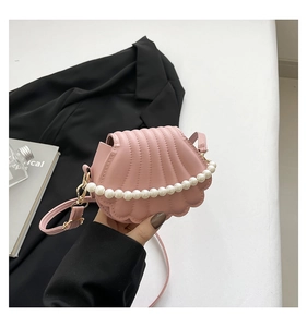 Detail of light pink shell crossbody bag with white pearl chain and matte leather texture