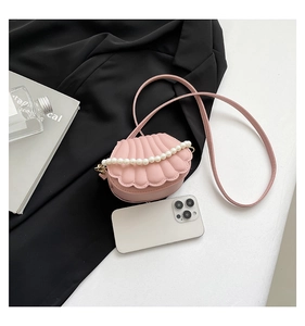 Mini pink shell bag with pearl handle and phone for size scale comparison