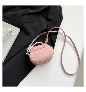 Detailed view of pink shell-shaped bag with pearl handle and leather shoulder strap