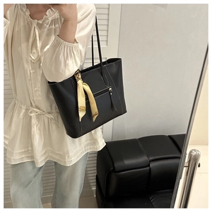 Detail of a large black tote bag with white contrast stitching and a floral silk scarf