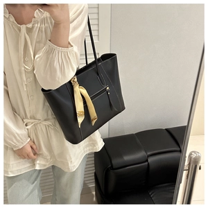 Detail of black tote bag with white stitching and decorative yellow silk scarf