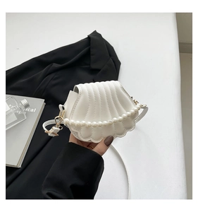 Detail of white shell-shaped evening bag with quilted texture and pearl handle