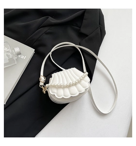 Close-up of shell-shaped white leather handbag with pearl chain and ruffled edges