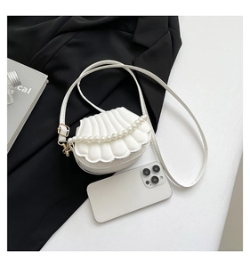 Detail of white shell-shaped bag with quilted texture and elegant pearl handle