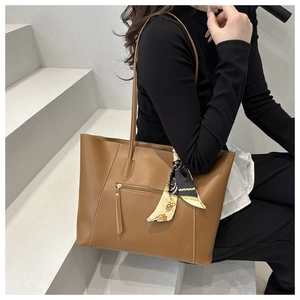 Detail of caramel leather tote bag with functional front zipper and silk scarf handle