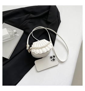 Detail view of white shell-shaped evening bag with quilted texture and elegant pearl handle