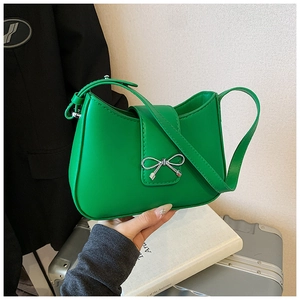 Détail d'un sac sous les bras vert vif en forme de croissant avec boucle nœud en argent