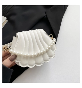 Detail of shell-shaped white pearl evening bag featuring gold metal hardware and luxury finish