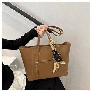 Detail of brown faux leather tote bag with zip pocket and stylish chain pattern scarf
