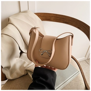Détail d'un sac sous les bras en cuir avec un nœud métallique et une finition beige-rose