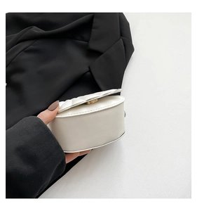 Detail of white shell-shaped bag with quilted diamond pattern and pearl chain strap