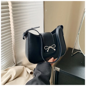 Détail du sac croissant en cuir noir brillant avec décoration de nœud en métal argenté