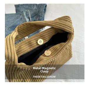 Detail of the magnetic snap closure on a khaki corduroy shoulder bag with retro texture