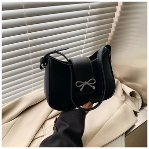 Détail du sac croissant en cuir noir avec un fermoir décoratif en forme de nœud argenté