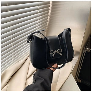 Gros plan du sac sous le bras en similicuir noir avec nœud argenté et détails de couture