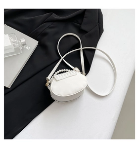 Detailed view of white shell bag with elegant pearl handle and pleated leather finish
