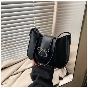 Détail du sac sous l'aisselle noir avec boucle nœud argentée et texture en cuir lisse