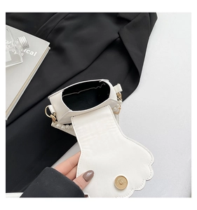 Detail of white shell handbag with pearl strap and gold magnetic closure mechanism