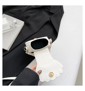 Detail of white shell-shaped evening bag featuring pearl handle and magnetic closure
