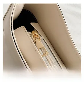 Detailed macro of smooth gold zipper and stitching on beige leather handbag