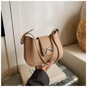 Détail d'un sac à bandoulière beige avec boucle noeud argentée et texture en cuir lisse