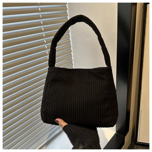 Detailed close-up of solid black corduroy shoulder bag with distinct vertical texture