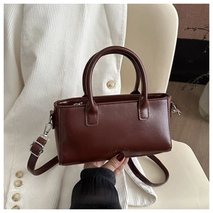 Close-up of brown leather handbag with FASHION embossing and circular handles