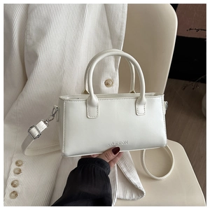 Detail of white leather shoulder bag featuring embossed FASHION text and adjustable strap